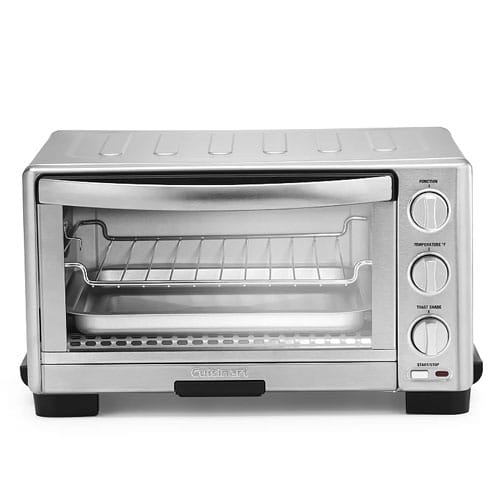 A compact stainless steel toaster oven with adjustable temperature, function, and timer dials, featuring a glass door and a wire rack inside.
