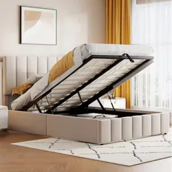 A beige upholstered bed with a lift-up storage compartment, featuring a mattress partially raised to reveal ample space underneath. The room includes yellow accents, a patterned rug, and a framed abstract artwork.