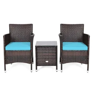 A patio set featuring two wicker chairs with turquoise cushions and a matching wicker side table, all with metal-capped legs for stability.