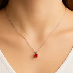 A necklace features a delicate chain with a small red spherical pendant, creating a simple yet elegant accessory.
