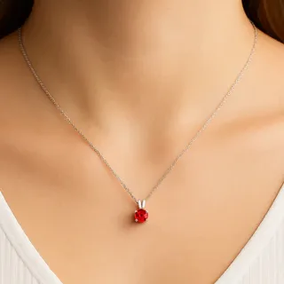 A necklace features a delicate chain with a small red spherical pendant, creating a simple yet elegant accessory.