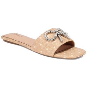 A beige slide sandal featuring a polka dot pattern and adorned with a rhinestone bow.
