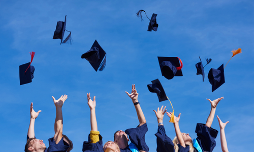hands throwing graduation caps blue sky