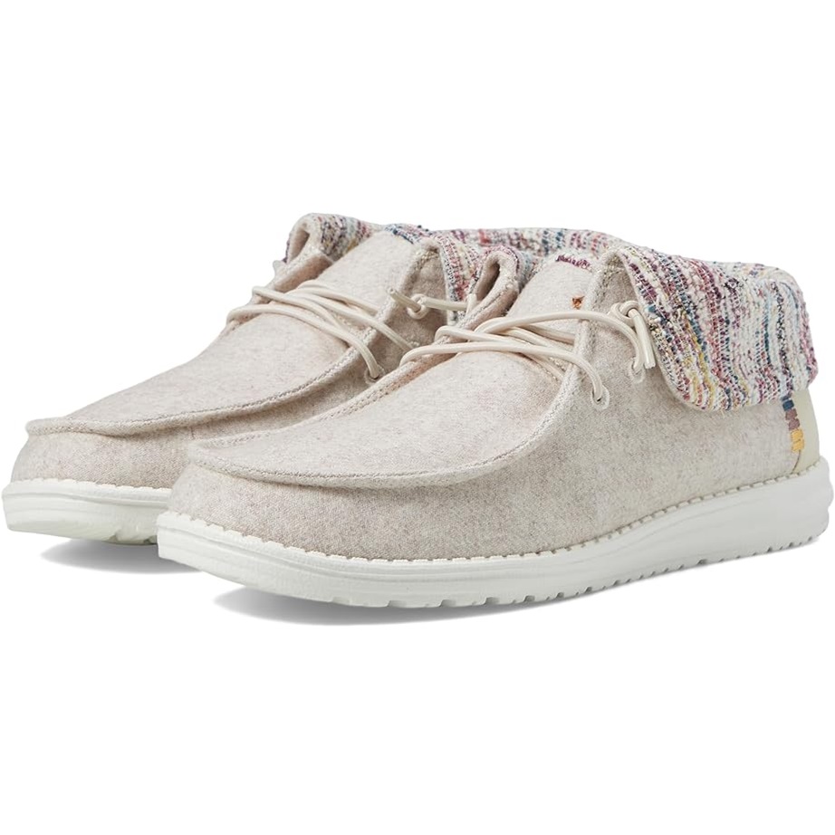 A pair of beige moccasin-style shoes with multicolored knitted detailing around the ankle.