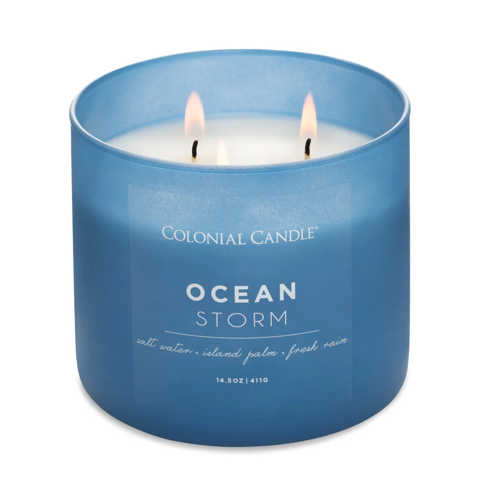 Blue Colonial Candle labeled \“Ocean Storm,\“ featuring scents of salt water, island palm, and fresh rain, with three wicks.