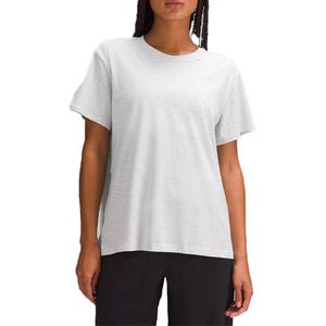A relaxed-fit white cotton t-shirt with short sleeves and a classic crew neckline, paired with black pants.