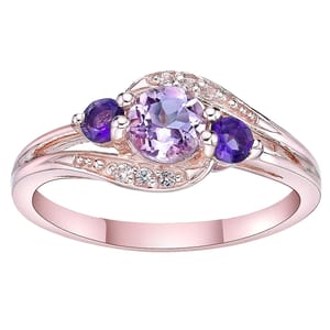 A pink amethyst and white topaz ring in rose gold with a central round pink amethyst flanked by two smaller purple stones and adorned with small white topaz accents along the band.