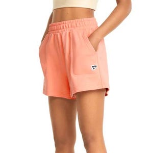 Peach-colored high-waisted shorts by Puma featuring an elastic waistband, side pockets, and a small logo patch on the left leg.