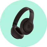 Black over-ear headphones with a prominent \“b\“ logo on the ear cups, set against a light green background.