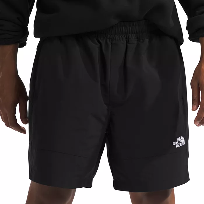 The North Face Men's Easy Wind Shorts are black with an elastic waistband and feature the brand's logo on the left leg. They offer a casual and comfortable fit suitable for various activities.