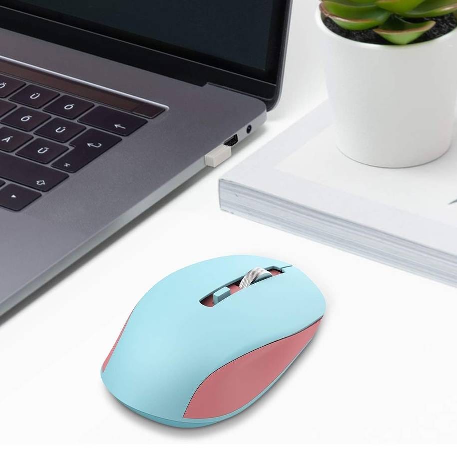 Wireless light blue and pink computer mouse on a desk near a laptop, a closed book, and a small potted plant.
