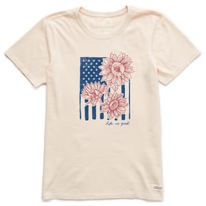 A beige T-shirt features a design of sunflowers overlaying a stylized American flag. The text \“Life is Good\“ is printed below the graphic.