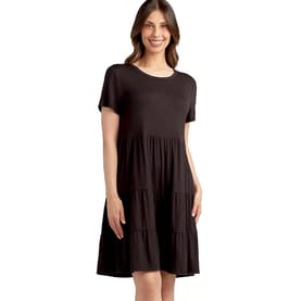 A woman is wearing a short-sleeved, knee-length black dress with a tiered skirt.