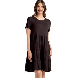 A woman is wearing a short-sleeved, knee-length black dress with a tiered skirt.