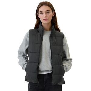 A woman is wearing a dark gray puffer vest over a light gray sweatshirt, paired with black pants.