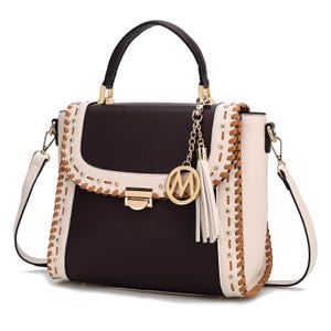 A stylish handbag with a black and white color scheme, featuring a top handle, detachable shoulder strap, stud detailing, and decorative charm with a tassel and circular emblem.