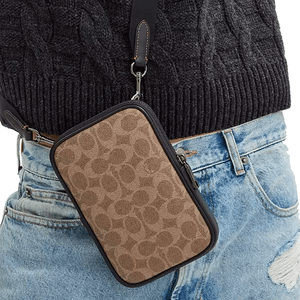 The Coach Outlet Aden Crossbody Bag features a compact design with a brown, signature canvas pattern and black leather trim, equipped with a detachable strap for versatile carrying options.