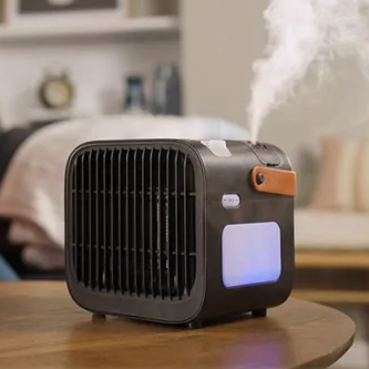 A portable air cooling device with a front vent, a handle on top, and emitting mist, placed on a table in a cozy room setting.