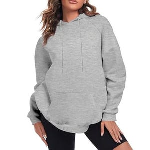 A gray hooded sweatshirt with drawstrings, worn by a model, paired with black shorts.