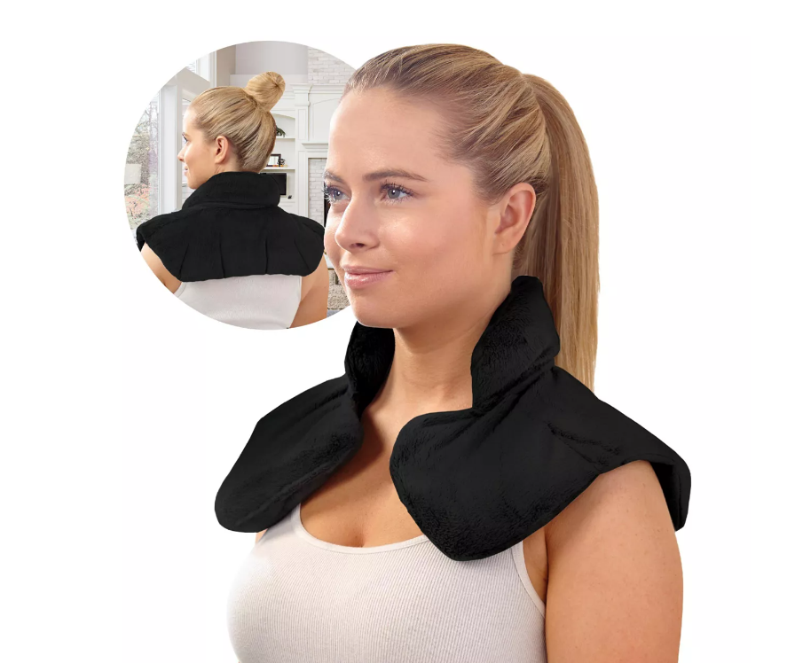 A woman wearing a black, shoulder-wrapping heating pad with a control unit.