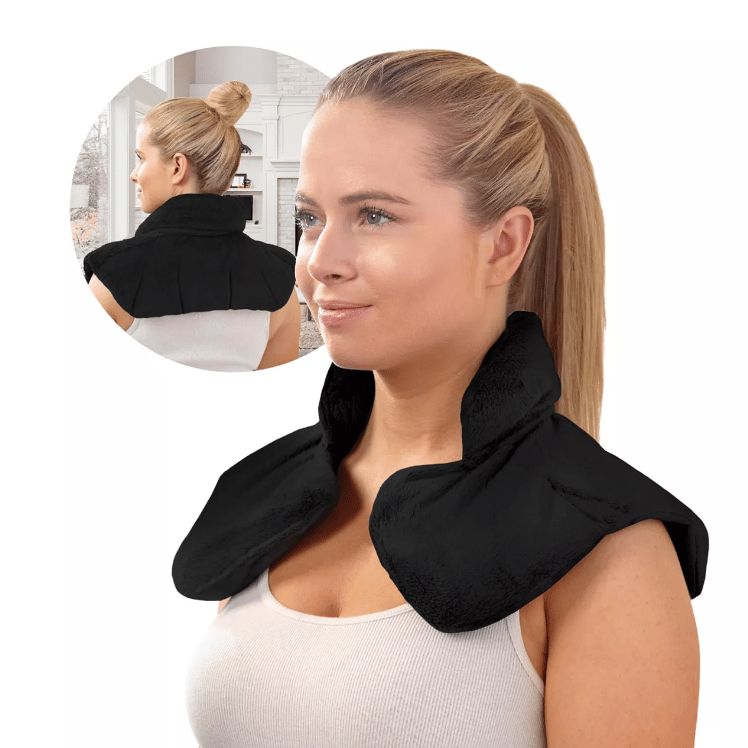 A woman wearing a black, shoulder-wrapping heating pad with a control unit.