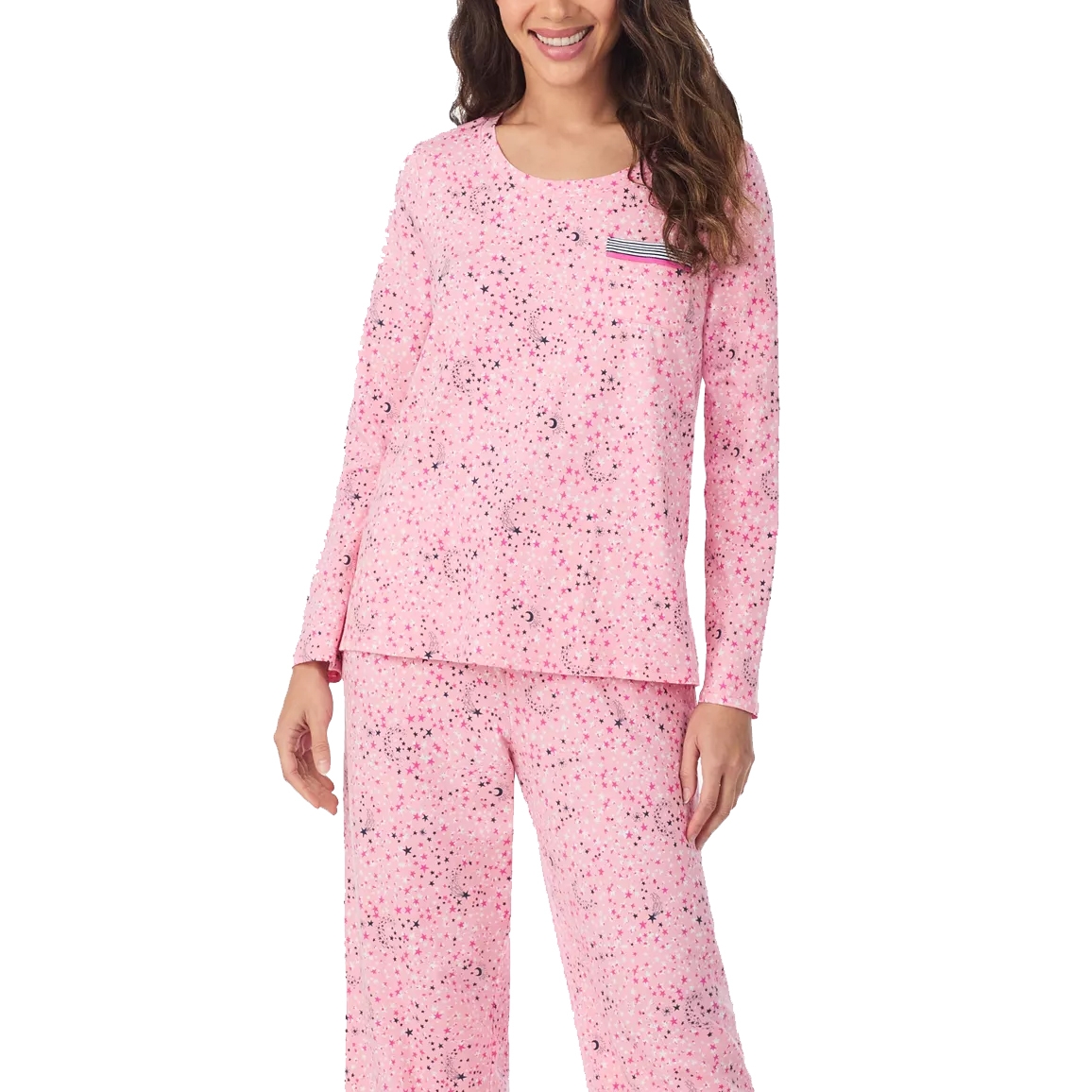 A woman is wearing a pink pajama set featuring a star and moon pattern with long sleeves and a small striped pocket on the top.