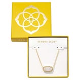 A Kendra Scott necklace with a gold chain and oval pendant is displayed in a yellow box featuring the brand's logo.