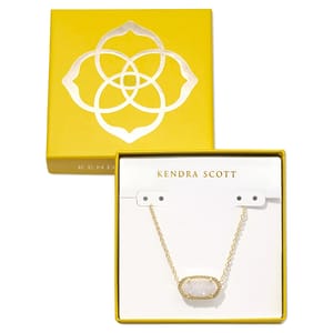 A Kendra Scott necklace with a gold chain and oval pendant is displayed in a yellow box featuring the brand's logo.