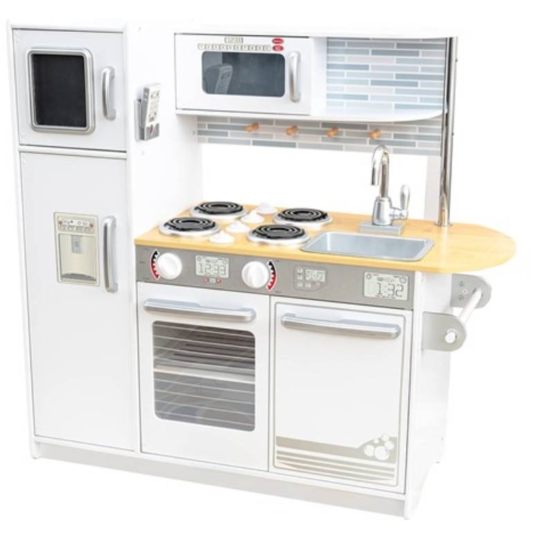 A KidKraft Wooden Play Kitchen features a fridge, microwave, oven, stovetop, sink, and counter space with a white and silver color scheme and gray brick-patterned backsplash.
