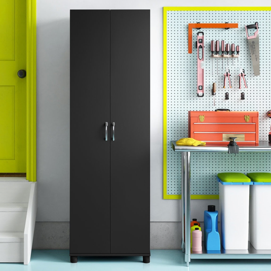 A sleek black storage cabinet is next to a bright yellow door and a pegboard with tools. A workbench holds an orange toolbox, and there are colorful bins and bottles below.