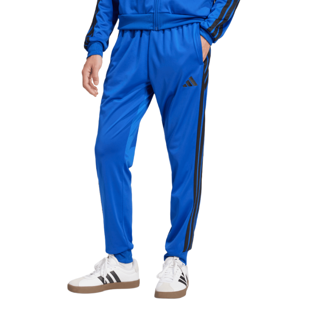 A person is wearing a blue Adidas tracksuit with black stripes and white Adidas sneakers.