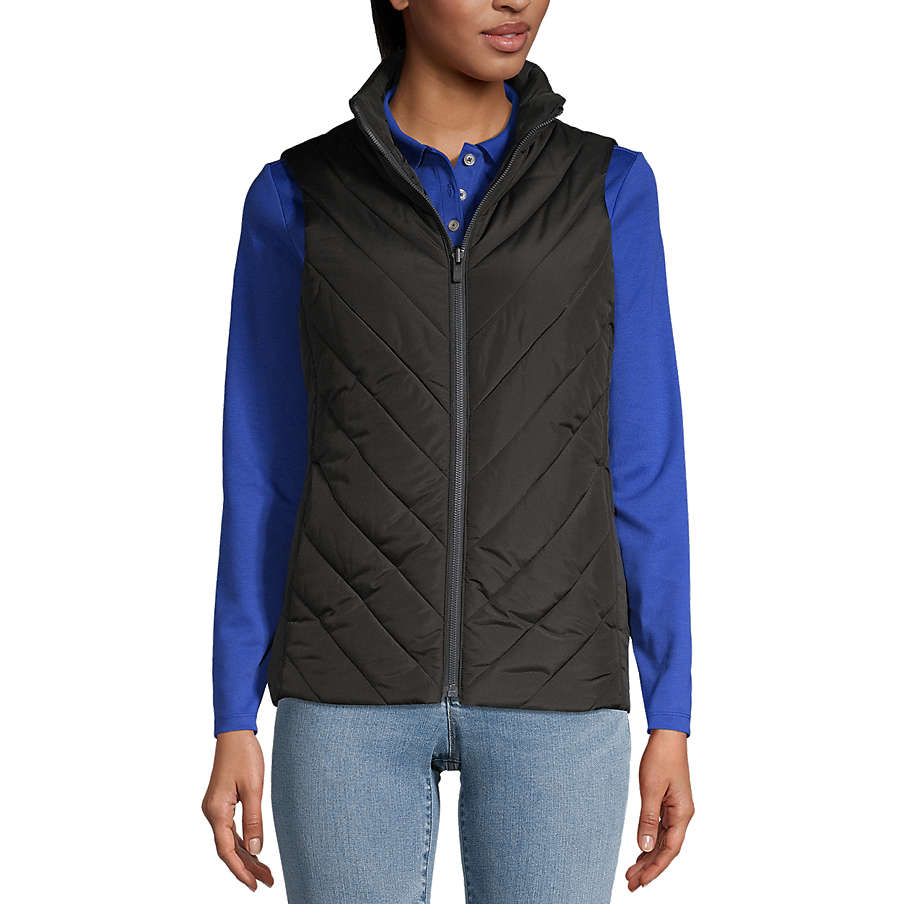 A woman wears a black quilted vest over a blue long-sleeve top with jeans.