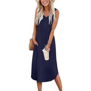 A woman in a sleeveless navy blue midi dress holds a cold drink and a small straw handbag, accessorized with a bracelet and a hat.