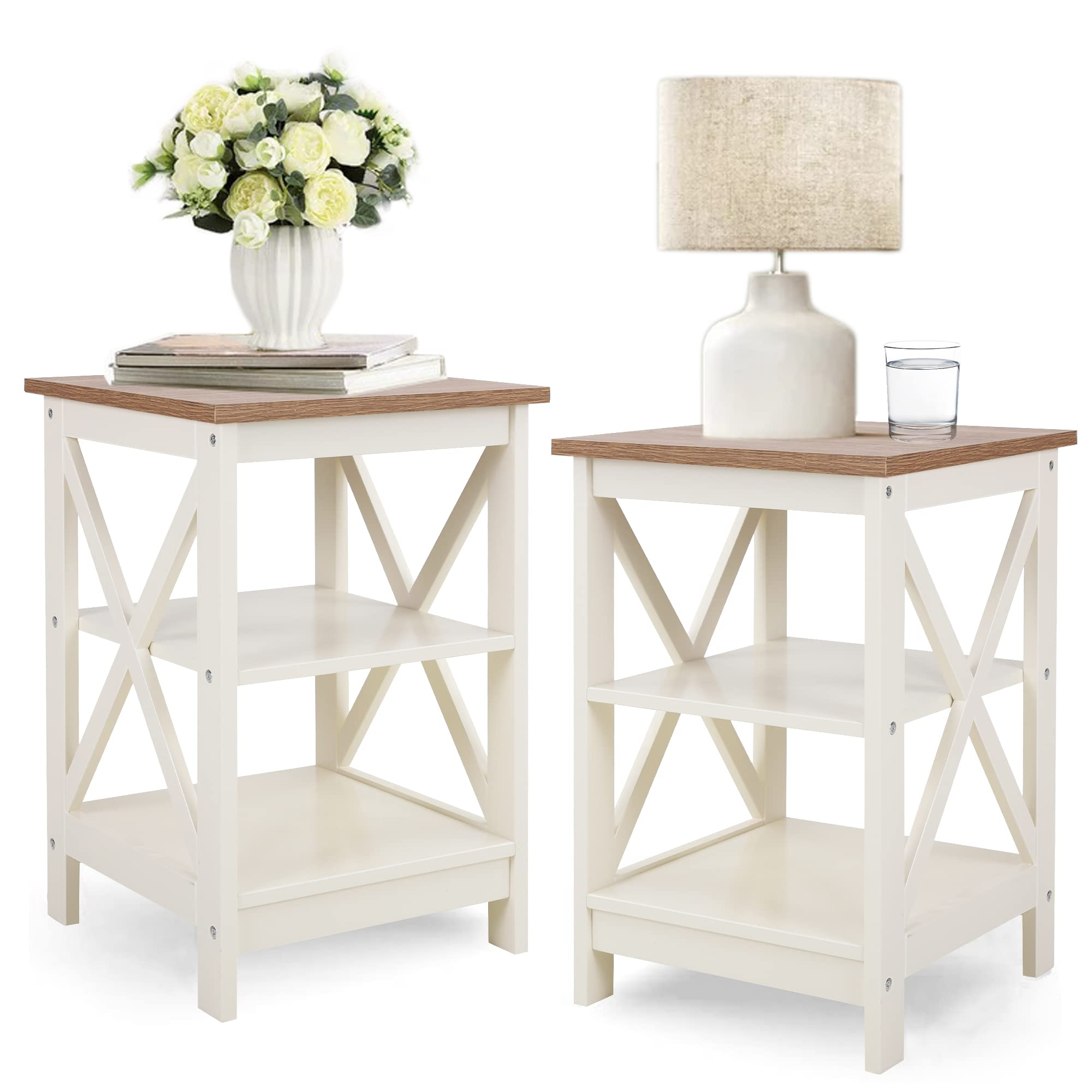Two small side tables with a white frame and a wood top, featuring X-shaped side braces. One table holds a lamp and a glass of water, the other a vase of flowers and books.