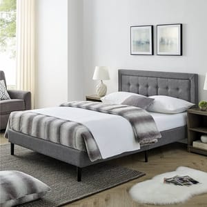A modern bedroom features a gray upholstered bed with a button-tufted headboard, white bedding, and a striped throw. Nightstands with lamps, abstract wall art, and a cozy atmosphere complete the look.