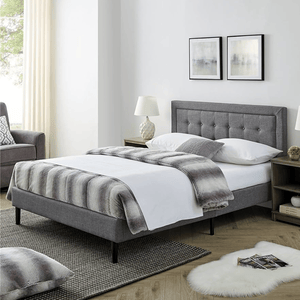 A modern bedroom features a gray upholstered bed with a button-tufted headboard, white bedding, and a striped throw. Nightstands with lamps, abstract wall art, and a cozy atmosphere complete the look.