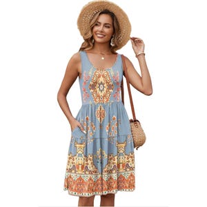 A sleeveless sundress with pockets featuring a colorful floral and geometric pattern on a blue background, paired with a straw hat and crossbody bag.