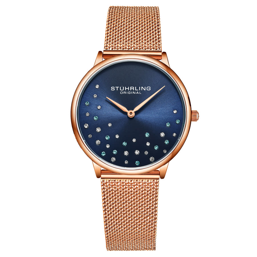 A rose gold mesh band wristwatch with a navy blue dial featuring decorative crystals and matching gold hands, branded with \“STÜHRLING ORIGINAL.\“