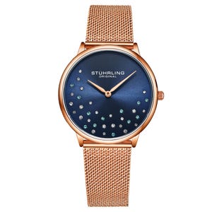 A rose gold mesh band wristwatch with a navy blue dial featuring decorative crystals and matching gold hands, branded with \“STÜHRLING ORIGINAL.\“