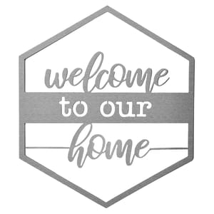 A hexagon-shaped metal door sign featuring the text \“welcome to our home\“ in a combination of script and print fonts.