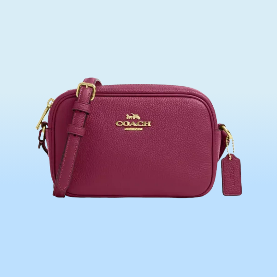 A maroon Coach crossbody bag with gold-tone hardware and an adjustable strap.