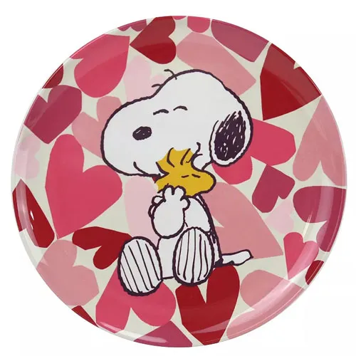 Round plate featuring a cartoon dog hugging a small yellow bird, set against a background of overlapping red and pink hearts.