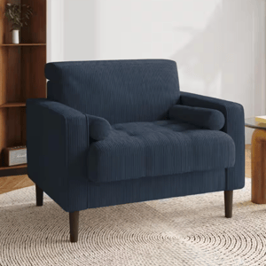 Mid-century style armchair with navy corduroy upholstery, featuring tufted cushions, rounded armrests, and wooden legs.