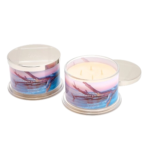 Two scented candles in glass jars with metallic lids, labeled \“Ocean Driftwood.\“ The jars feature a design with driftwood and a blue ocean theme.