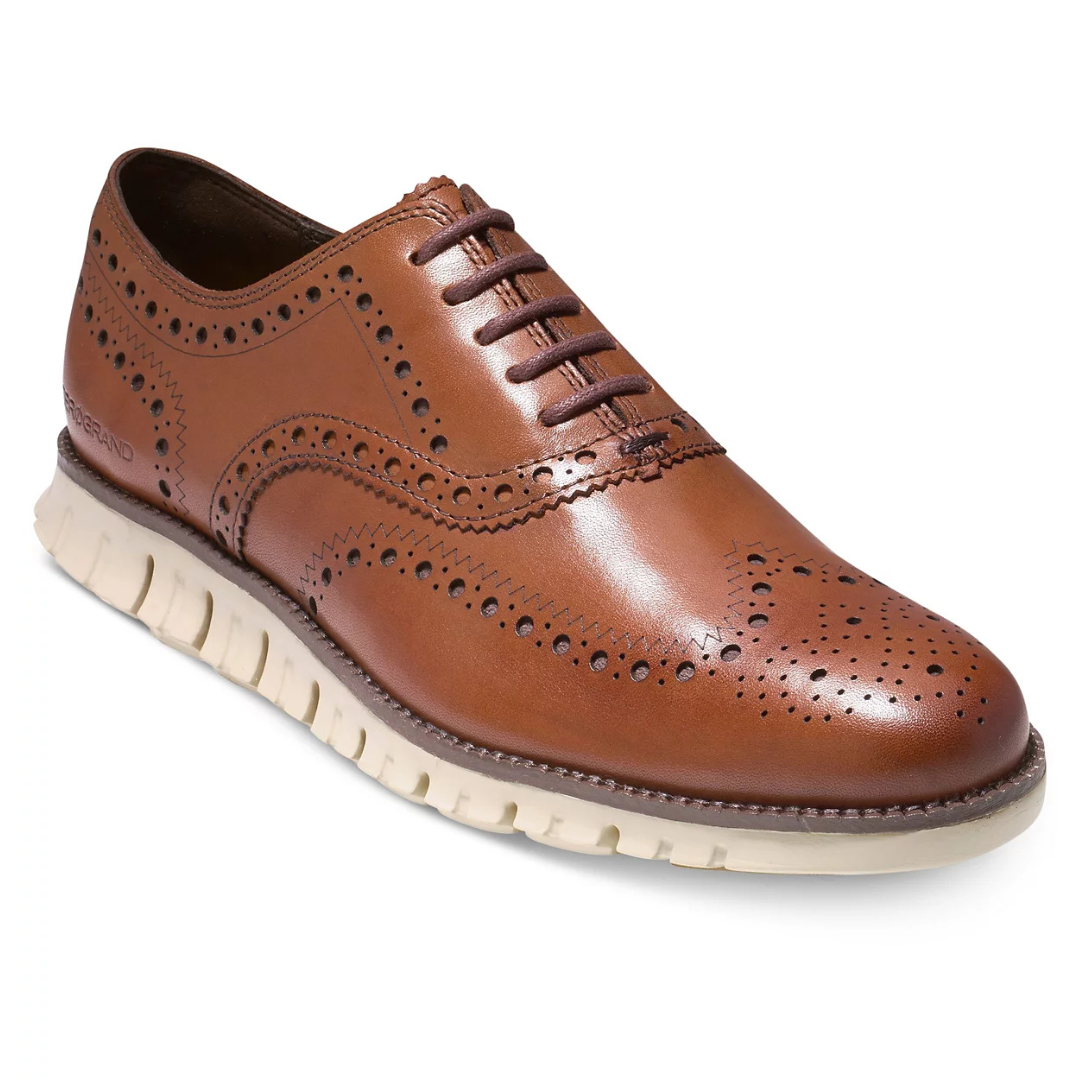 Brown leather wingtip oxford with perforated detailing and a white, flexible rubber sole.