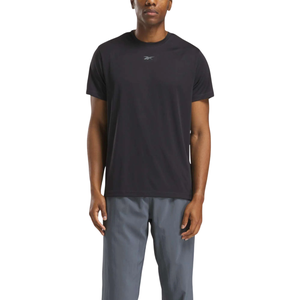 A person wearing a black Reebok t-shirt and gray pants. The t-shirt features a small Reebok logo on the chest.