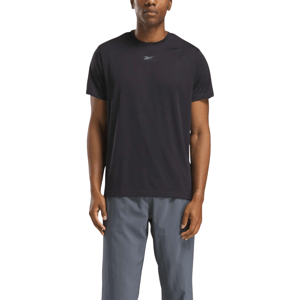 A person wearing a black Reebok t-shirt and gray pants. The t-shirt features a small Reebok logo on the chest.