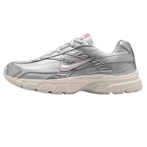 A silver athletic sneaker with a white sole featuring a light pink swoosh logo and red branding on the tongue. The design includes detailed stitching and layered accents.