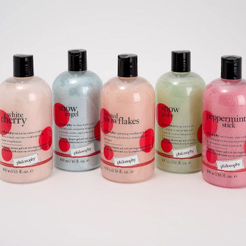 five multicolored shower gels on a grey background