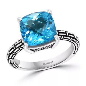 Effy Blue Topaz Statement Ring features a large, cushion-cut blue topaz mounted on an ornately designed silver band with a geometric pattern.